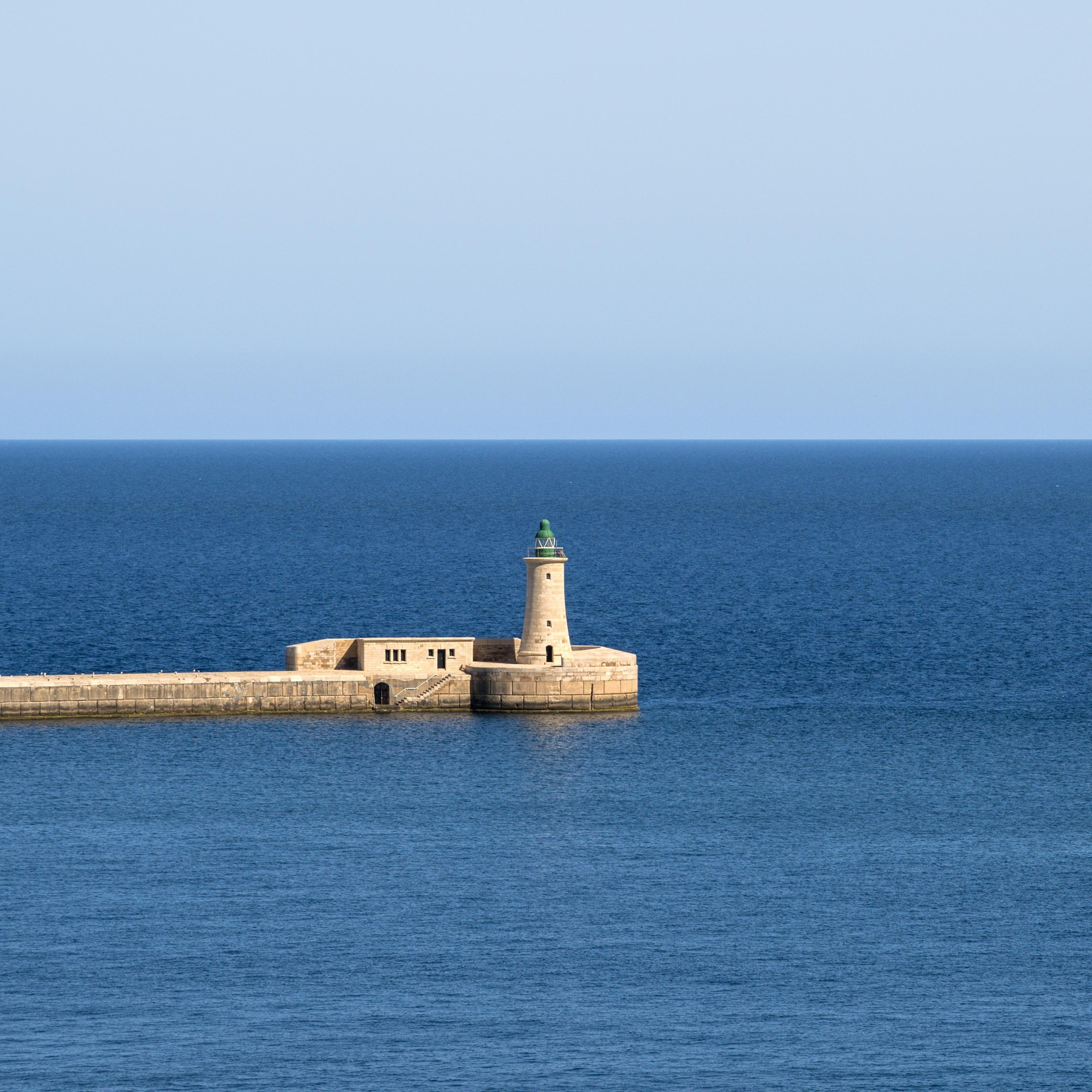 Malta's Historic Fort and Lighthouse Overlooking Azure Waters