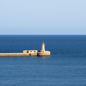 Malta's Historic Fort and Lighthouse Overlooking Azure Waters